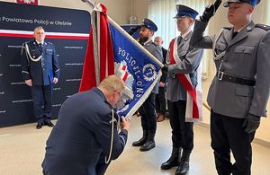 Zdjęcie w kolorze przedstawia uroczystą zbiórkę z udziałem pocztu sztandarowego KPP w Oleśnie , Komendant w ukłonie przed sztandarem.