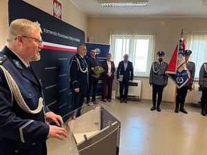 Zdjęcie w kolorze przedstawia uroczystą zbiórkę z udziałem pocztu sztandarowego KPP w Oleśnie, Komendant stoi przy mównicy kadr z bliska.