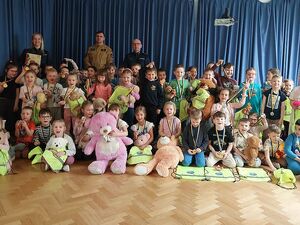 Zdjęcie w kolorze, przedstawia   przedszkolaków pozujących do wspólnego zdjęcia z funkcjonariuszami.