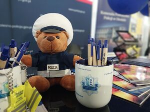 Zdjęcie w kolorze przedstawia materiały promocyjne KPP w Oleśnie oraz maskotkę - misia w stroju policjanta ruchu drogowego.
