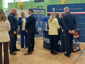 Zdjęcie w kolorze przedstawia policyjne stoisko promocyjne, przy którym przebywają uczestnicy wydarzenia z policjantami.
