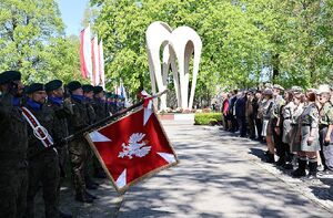 Zdjęcie w kolorze przedstawia uczestników uroczystości, na pierwszym planie sztandar z godłem polski.