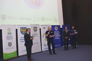 Zdjęcie w kolorze przedstawia salę kinową na środku osoby mówiące do mikrofonu.