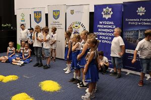 Zdjęcie w kolorze przedstawia salę kinową na środku przedszkolaki wykonujące przedstawienie.