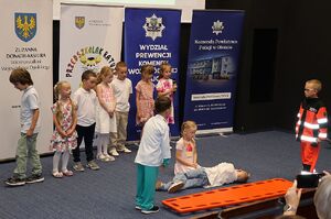 Zdjęcie w kolorze przedstawia salę kinową na środku przedszkolaki wykonujące przedstawienie.