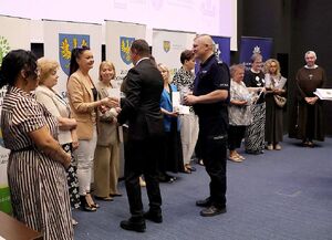 Zdjęcie w kolorze przedstawia osoby wręczające upominki dla zaproszonych gości.
