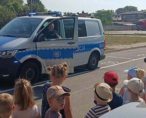 Zdjęcie w kolorze przedstawia radiowóz oraz dzieci
