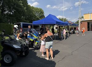 Zdjęcie w kolorze przedstawia plac zewnętrzny KPPSP w Oleśnie na którym prezentowane są pojazdy oraz sprzęt służb - Policji i Straży Pożarnej.