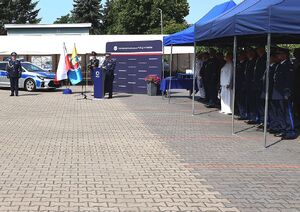Zdjęcie w kolorze przedstawia  Zastępcę Komendanta Wojewódzkiego Policji w Opolu stojącego przy mównicy, w tle niebieska ściana z płótna.