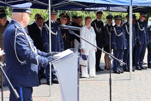 Zdjęcie w kolorze przedstawia  Zastępcę Komendanta Wojewódzkiego Policji w Opolu stojącego przy mównicy, w tle stojący pod namiotem goście oraz policjanci.