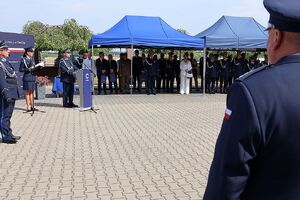 Zdjęcie w kolorze przedstawia  Zastępcę Komendanta Wojewódzkiego Policji w Opolu stojącego przy mównicy, w tle policjanci i zgromadzeni goście.