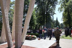 Zdjęcie w kolorze przedstawia obchody Święta Wojska Polskiego - komendant niesie kwiaty na pomnik