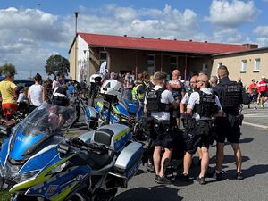 Zdjęcie w kolorze przedstawia policjantów ruchu drogowego i drużyny rowerowej podszas przerwy z uczestnikami rajdu.