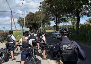 Zdjęcie w kolorze przedstawia policjantów drużyny rowerowej i ruchu drogowego którzy stoją na jezdni przygotowują się do kontynuowania rajdu.