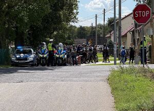 Zdjęcie w kolorze przedstawia policjantów ruchu drogowego którzy stoją na jezdni, obok nich uczestnicy rajdu formują peleton.