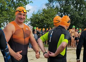 Zdjęcie w kolorze przedstawia uczestników triathlonu ubranych w stroje pływackie.
