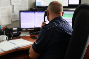 Zdjęcie przedstawia oficera dyżurnego trzymającego przy uchu słuchawkę telefonu.