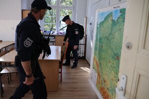 Zdjęcie przedstawia policjantów przeszukujacych klasę