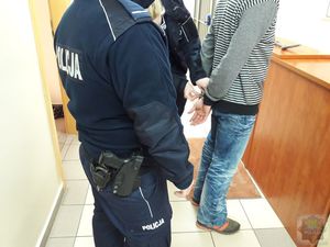 Policjanci zakładają zatrzymanemu kajdanki na ręce trzymane z tyłu