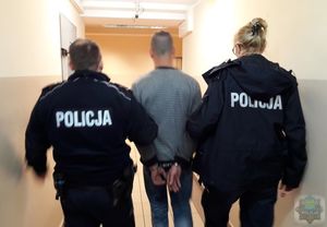 policjanci prowadzą zatrzymanego korytarzem