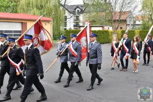 maszerujące po placu Państwowej Straży Pożarnej w Oleśnie poczty sztandarowe na pierwszym planie strażacy następnie policjanci a dalej uczniowie szkół średnich.