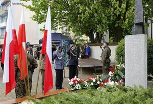 Przedstawiciele Straży Pożarnej, Wojska Polskiego, Policji i Straży Miejskiej oddają honory przed pomnikiem Papieża Jana Pawła 2 w tle mieszkańcy Olesna