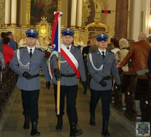 Poczet sztandarowy oleskiej komendy wychodzi z kościoła pod wezwaniem Bożego Ciała. Policjanci niosą sztandar jednostki.