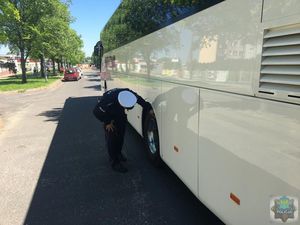 Policjant ruchu drogowego sprawdza bieżnik opony w autokarze