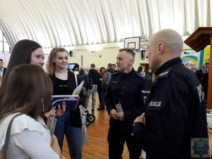 Policjanci na Powiatowych Targach Pracy rozmawiają z uczniami liceum promując swoją służbę