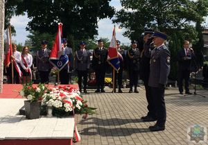 Komendant Powiatowy Policji i  Komendant Straży Pożarnej oddają honory przy Pomniku Lotników Polskich , w tle poczty sztandarowe .