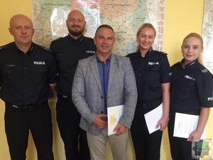 Dwaj policjanci i dwie policjantki  stoją w szeregu pod ścianą, po środku komendant 1 Zastępca KWP insp. Adam Tychowicz. Wszyscy się uśmiechają.