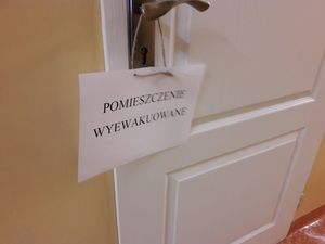 Papierowa kartka z napisem &quot; pomieszczenie wyewakuowane&quot; zawieszona na klamce jednych z drzwi w szpitalu.