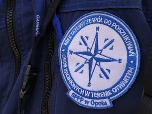 Plakietka na mundurze policjanta. Na niebieskim tle napis Nieetatowy Zespół Do Poszukiwań Osób Zaginionych w Terenie Otwartym SPPP Opole.