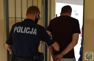 Policjant wyprowadza zatrzymanego z policyjnego aresztu.