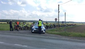 Uczestnicy rajdu stoją przed skrzyżowaniem. Przed nimi radiowóz i dwóch policjantów.