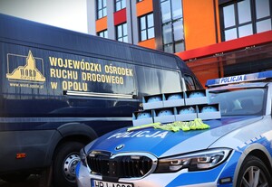 zdjęcie kolorowe: policjanci rozdają dzieciom kaski i elementy odblaskowe